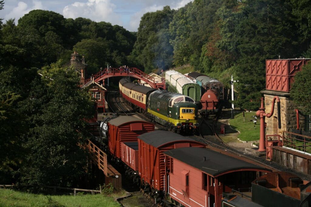 Aerial view of historical steam trains on North York Moors Railway in a lush, green setting.