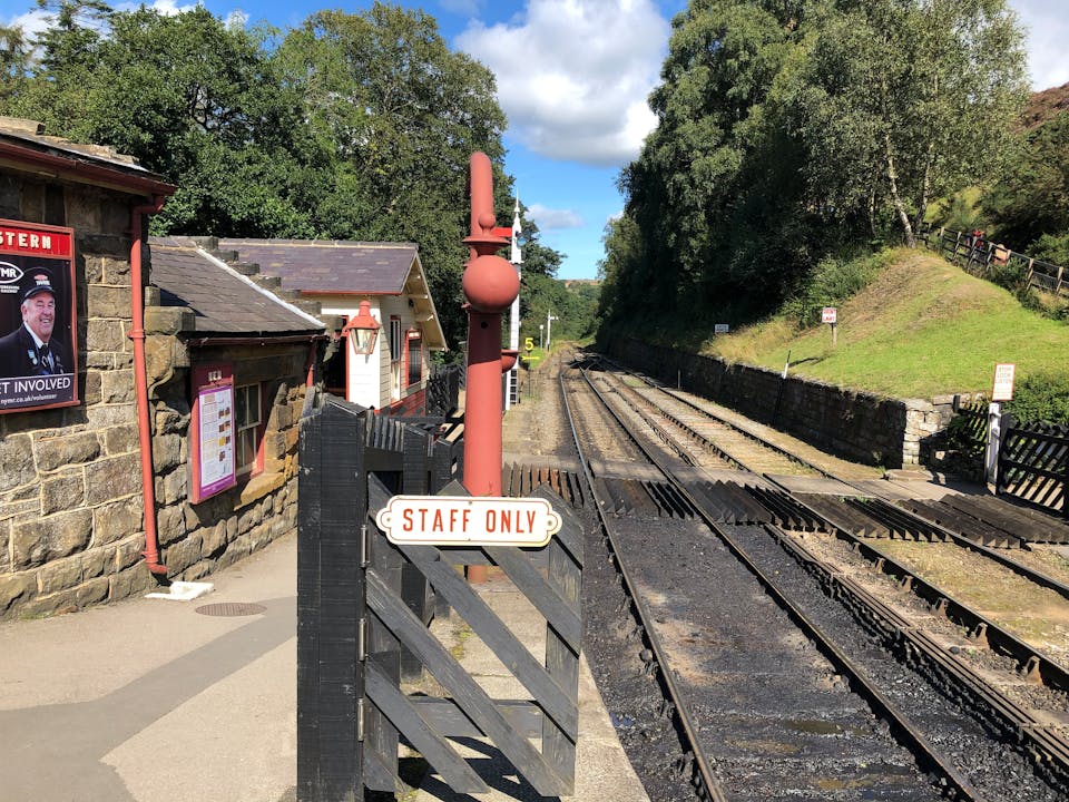 Charming view of Goathland railway platform with vintage elements, trees, and tracks in England.