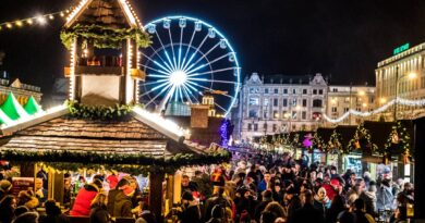 Crowded night market with neon lights and ferris wheel creating a festive atmosphere.