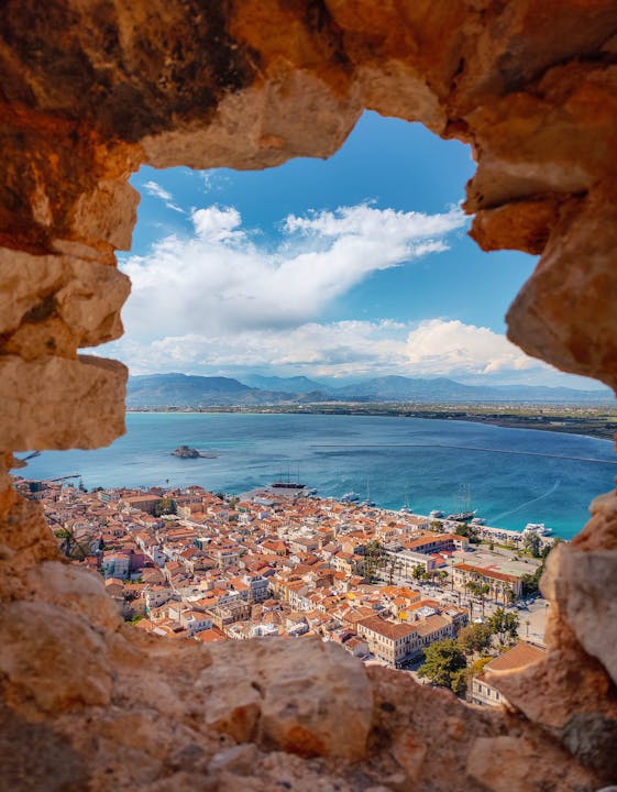 A breathtaking seaside town seen through a historic stone ruin, overlooking the serene blue sea.