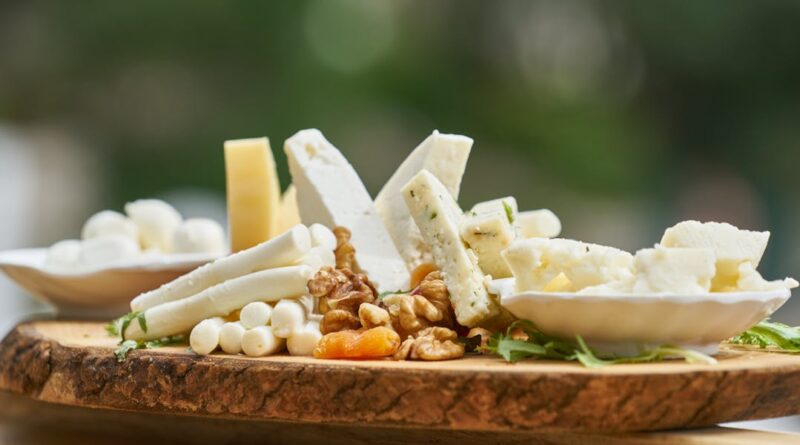 A delicious assortment of cheese and nuts on a rustic wooden board, perfect for appetizers.