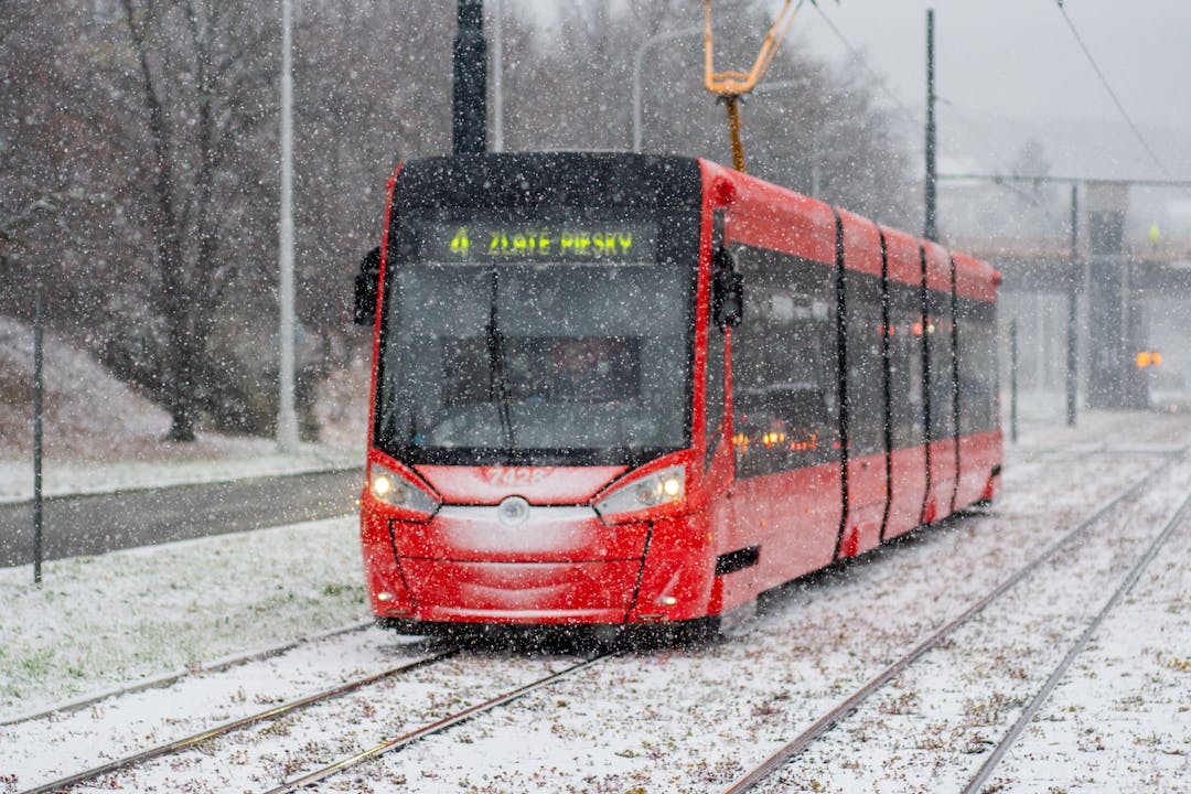 A red tram travels through a snowy street in Bratislava, Slovakia, during winter.