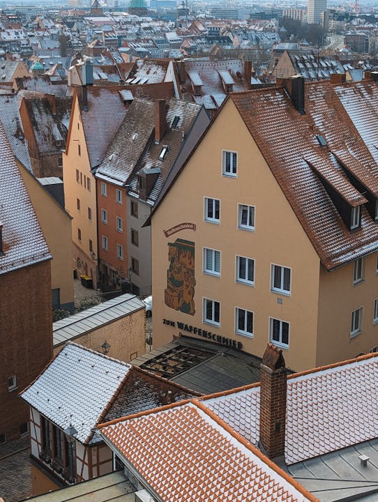 Aerial view of snow-dusted rooftops and medieval buildings in Nuremberg, Germany, creating a serene winter cityscape.