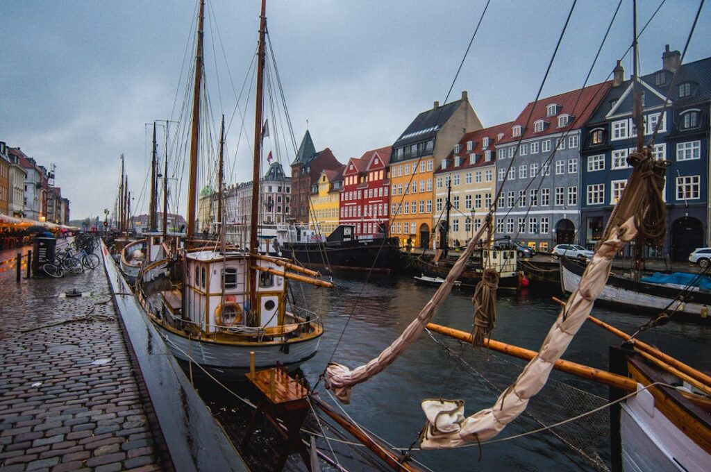 Vibrant Nyhavn harbor in Copenhagen with docked boats against colorful historic buildings.