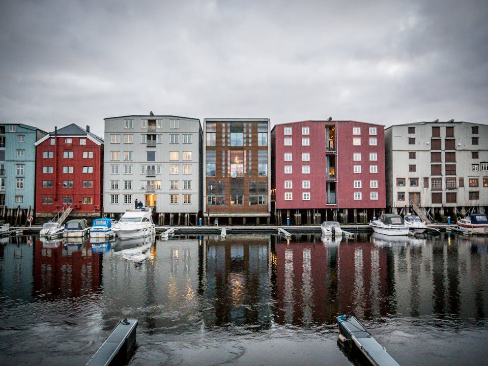 Vibrant modern waterfront buildings reflecting on the water in Trondheim, Norway at dusk.