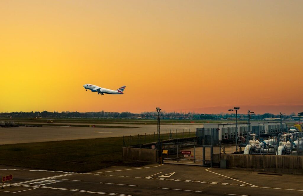 Airplane ascending during sunset at Heathrow Airport, capturing the vibrant sky.