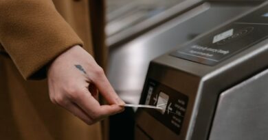 A person inserting a ticket into a turnstile at a train station, showcasing public transportation usage.
