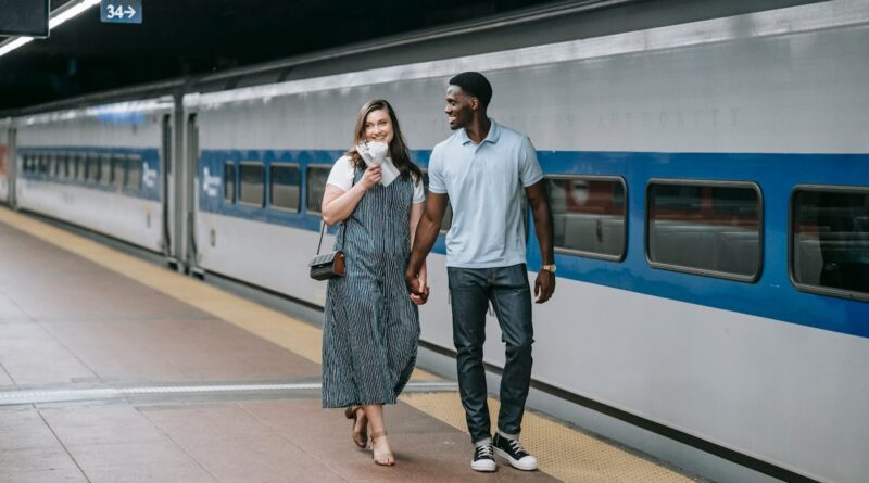 A happy couple walking hand in hand along a train platform, exuding joy and connection.