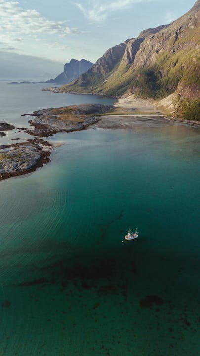 Drone view over Bodø, Norway showcasing a pristine fjord with a lone boat.